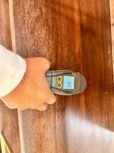 Inspector measuring wood moisture content with a moisture meter