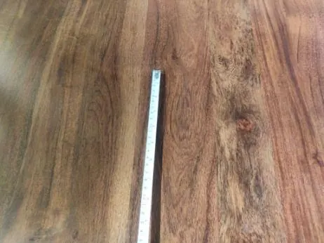 Major defect: visible epoxy (araldite) filling on a dining table top, measured against a tape
