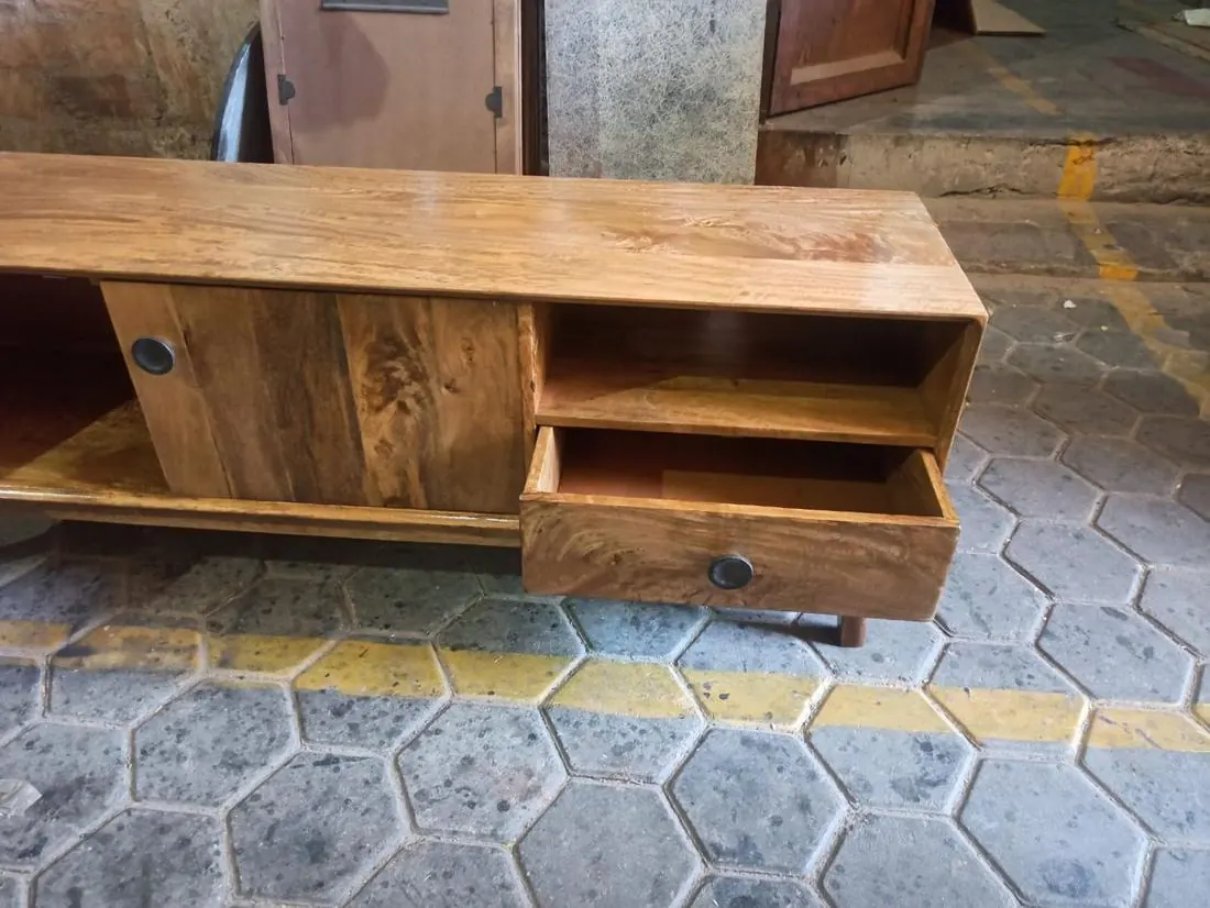 Solid wood TV unit with drawer open during inspection